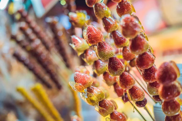 Frutas e bagas cristalizadas chinesas, espinheiro e morangos em gergelim e xarope de açúcar. Conceito de comida de rua chinesa — Fotografia de Stock