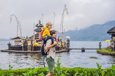 Baba ve oğul Pura Ulun Danu Bratan, Bali arka planda. Hindu Tapınağı çiçek Bratan Gölü, Bali çevrili. Shivaite su Tapınağı Bali, Endonezya Binbaşı. Hindu Tapınağı. Birlikte yolculuk