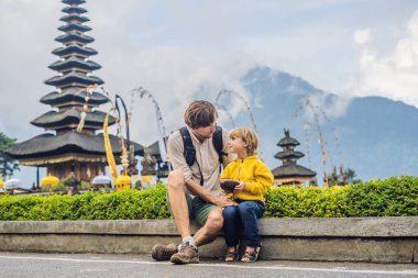Baba ve oğul Pura Ulun Danu Bratan, Bali arka planda. Hindu Tapınağı çiçek Bratan Gölü, Bali çevrili. Shivaite su Tapınağı Bali, Endonezya Binbaşı. Hindu Tapınağı. Birlikte yolculuk