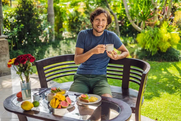 Um homem está tomando café da manhã no terraço — Fotografia de Stock