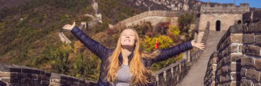 Happy cheerful joyful tourist woman at Great Wall of China having fun on travel smiling laughing and dancing during vacation trip in Asia. Girl visiting and sightseeing Chinese destination BANNER clipart