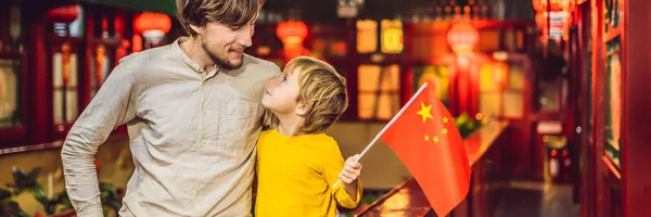 Desfrutando de férias na China. Turistas felizes pai e filho com uma bandeira chinesa em um fundo chinês. Viaje para a China com conceito de crianças. Trânsito livre de vistos 72 horas, 144 horas na China BANNER, LONG — Fotografia de Stock