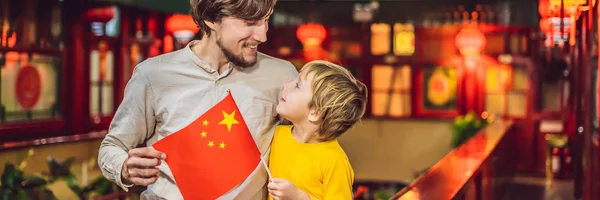 Enjoying vacation in China. Happy tourists dad and son with a Chinese flag on a Chinese background. Travel to China with kids concept. Visa free transit 72 hours, 144 hours in China BANNER, LONG