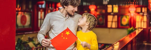 Enjoying vacation in China. Happy tourists dad and son with a Chinese flag on a Chinese background. Travel to China with kids concept. Visa free transit 72 hours, 144 hours in China BANNER, LONG