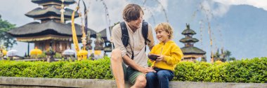 Baba ve oğul Pura Ulun Danu Bratan, Bali arka planda. Hindu Tapınağı çiçek Bratan Gölü, Bali çevrili. Shivaite su Tapınağı Bali, Endonezya Binbaşı. Hindu Tapınağı. Birlikte yolculuk