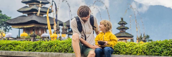 Papá e hijo en el fondo de Pura Ulun Danu Bratan, Bali. Templo hindú rodeado de flores en el lago Bratan, Bali. Mayor templo de agua Shivaite en Bali, Indonesia. Templo hindú. Viajar con —  Fotos de Stock