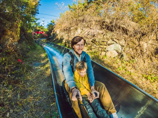 Dad and son have fun on alpine roller coaster — Stock Photo, Image