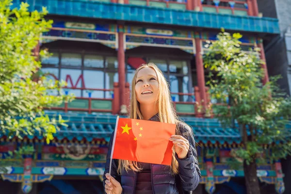 Godendo le vacanze in Cina. Giovane donna con bandiera nazionale cinese sullo sfondo della vecchia strada cinese. Viaggio in Cina concetto. Transito senza visto 72 ore, 144 ore in Cina — Foto Stock