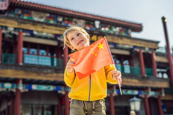 Godendo le vacanze in Cina. Ragazzo con bandiera nazionale cinese sullo sfondo della vecchia strada cinese. Viaggio in Cina concetto. Transito senza visto 72 ore, 144 ore in Cina — Foto Stock