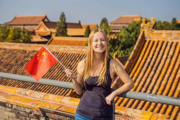 Enjoying vacation in China. Young woman with national chinese flag in Forbidden City. Travel to China concept. Visa free transit 72 hours, 144 hours in China