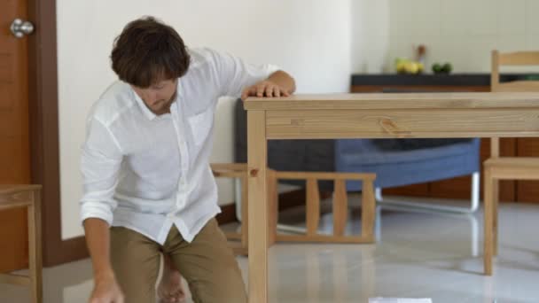 Een jongeman professionele meubilair assembler assembleert een houten tafel in een keuken — Stockvideo