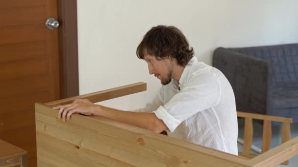 A young man professional furniture assembler assembles a wooden table in a kitchen — Stock Video