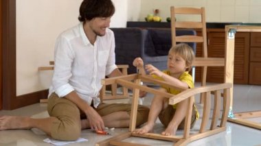 Baba ve oğul ahşap mobilya küçük parçalar bir araya getirin. Küçük çocuk babası bir sandalye bir araya yardımcı olur..