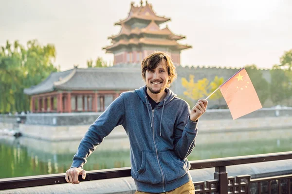 Enjoying vacation in China. Young man with national chinese flag in Forbidden City. Travel to China concept. Visa free transit 72 hours, 144 hours in China