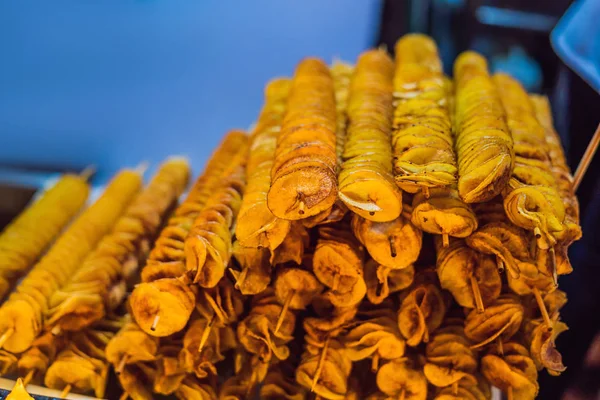 Spiral potatoes fried, on wooden sticks, spiral. Selling food at the market. Unhealthy fried food. Street food, a spiral fried potato on a stick — Stock Photo, Image