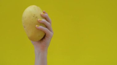 Bir kadının elinde sarı bir arka plan üzerinde sarı mango dans