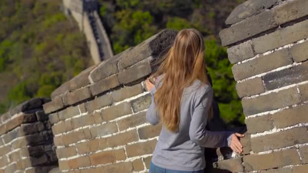 Steadycam shot of a young woman looking throug the opening of the China great wall. The wall rises up the side of the mountain in a begining of fall — Stock Video