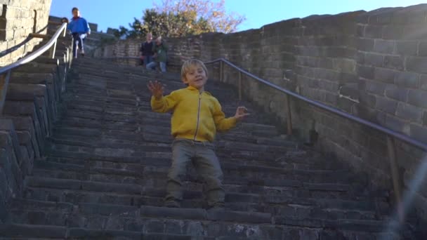 ПЕКИН, КИТАЯ - 27 ОКТЯБРЯ 2018: Медленный снимок счастливого маленького мальчика, веселящегося на лестнице Китайской Великой стены — стоковое видео