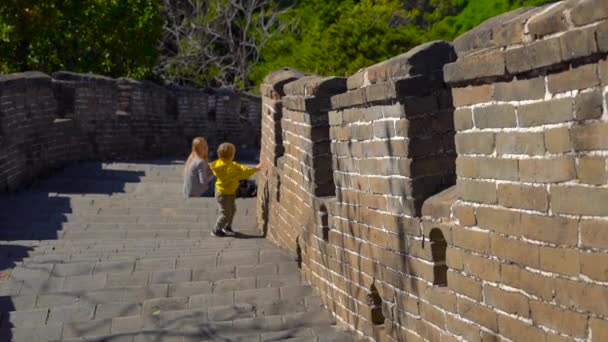 缓慢的稳定拍摄的中国长城 上升到山边 一个年轻的女人和她的小儿子在墙的楼梯上休息一下 — 图库视频影像