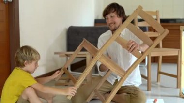 Baba ve oğul ahşap mobilya küçük parçalar bir araya getirin. Adam ve çocuk birbirlerine beş sandalye bitirdikten sonra araya vermek.