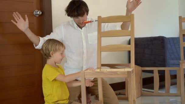 Baba ve oğul küçük parçalar ahşap mobilya montajı sırasında iyi eğlenceler. Küçük çocuk babası bir sandalye bir araya yardımcı olur..