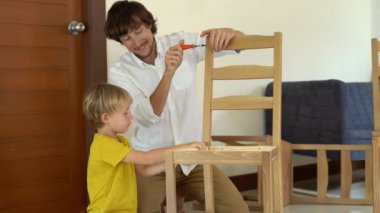 Baba ve oğul ahşap mobilya küçük parçalar bir araya getirin. Küçük çocuk babası bir sandalye bir araya yardımcı olur..