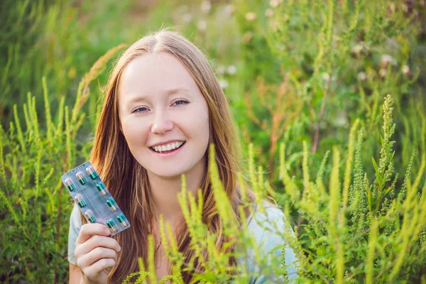 Mulher jovem segura em sua mão comprimidos de alergia por causa de uma alergia ao ragweed — Fotografia de Stock