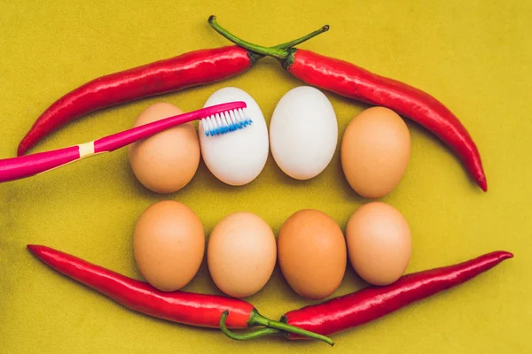 Eggs and red pepper in the form of a mouth with teeth. White eggs are bleached teeth. Yellow eggs - before bleaching. Teeth whitening before and after