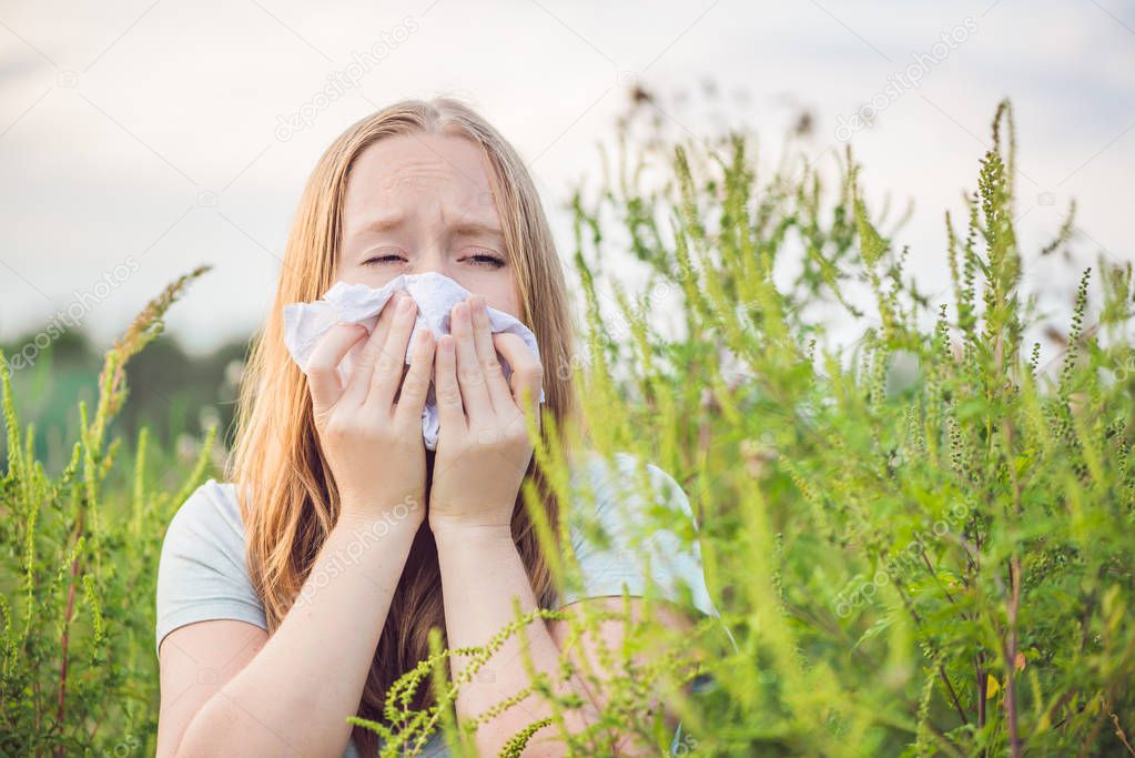 Young woman sneezes because of an allergy to ragweed