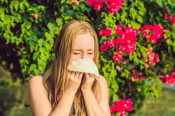 Konsep alergi serbuk sari. Wanita muda akan bersin. Pohon berbunga di latar belakang — Stok Foto