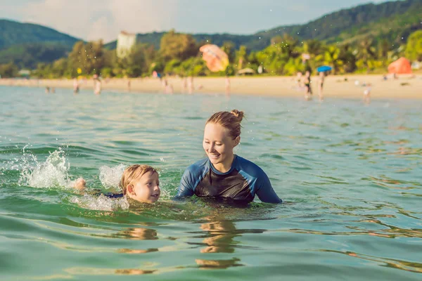 Donna istruttrice di nuoto per bambini sta insegnando a un ragazzo felice a nuotare nel mare — Foto Stock