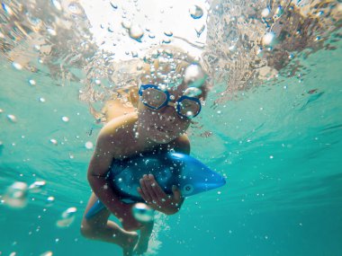 Gülümseyen ve gözlük yüzme ile umutla bir çocuk çocuk su altında bir havuzda yüzüyor