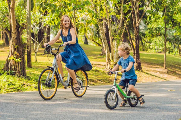 Ευτυχισμένη οικογένεια είναι ιππασία ποδήλατα στην ύπαιθρο και να χαμογελά. Μαμά σε ένα ποδήλατο και το γιο του σε μια balancebike — Φωτογραφία Αρχείου