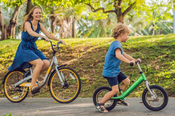 Šťastná rodina je na kolech venku a usmíval se. Máma na kole a syn na to balancebike — Stock fotografie