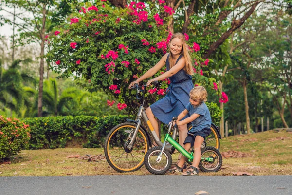 Ευτυχισμένη οικογένεια είναι ιππασία ποδήλατα στην ύπαιθρο και να χαμογελά. Μαμά σε ένα ποδήλατο και το γιο του σε μια balancebike — Φωτογραφία Αρχείου