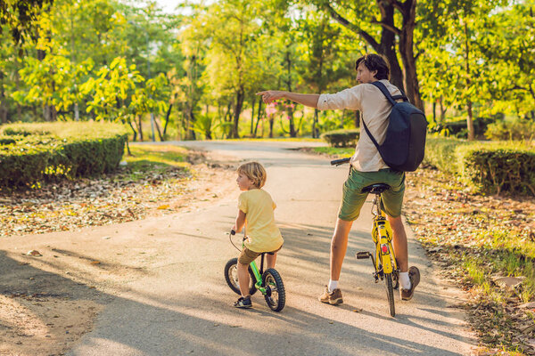 Happy family is riding bikes outdoors and smiling. Father on a bike and son on a balancebike