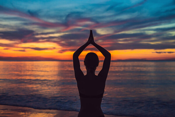 Young healthy woman practicing yoga on the beach at sunrise, benefits of natural environments for physical