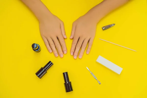 Mulher Mãos Cuidadas. Visão superior de belas mãos suaves das mulheres com ferramentas profissionais de cuidados de unhas para manicure em fundo amarelo. Closeup de unhas femininas saudáveis com prego amarelo polonês. Alto — Fotografia de Stock