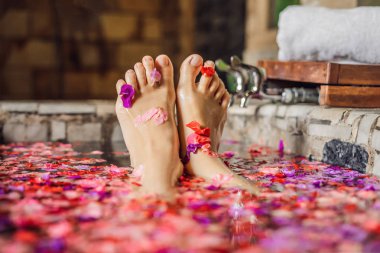 Banyo yaprakları tropikal çiçek ve aroma yağları ile çekici genç kadın. Spa uygulamaları için cilt yenileme. Spa salonu çekici kadın. Lüks spa ve Cilt Bakımı