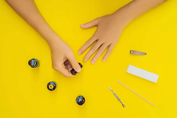 Woman Hands Care. Top View Of Beautiful Smooth Womans Hands With Professional Nail Care Tools For Manicure On yellow Background. Closeup Of Healthy Female Nails With yellow Nail Polish. High