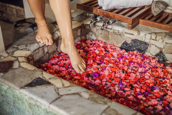 Atractiva Mujer joven en baño con pétalos de flores tropicales y aceites aromáticos. Tratamientos spa para el rejuvenecimiento de la piel. Mujer atractiva en el salón de Spa. Spa de lujo y cuidado de la piel —  Fotos de Stock