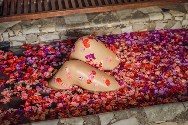 Mulher jovem atraente em banho com pétalas de flores tropicais e óleos de aroma. Tratamentos de spa para rejuvenescimento da pele. Uma mulher sedutora no salão de Spa. Spa de luxo e cuidados com a pele — Fotografia de Stock