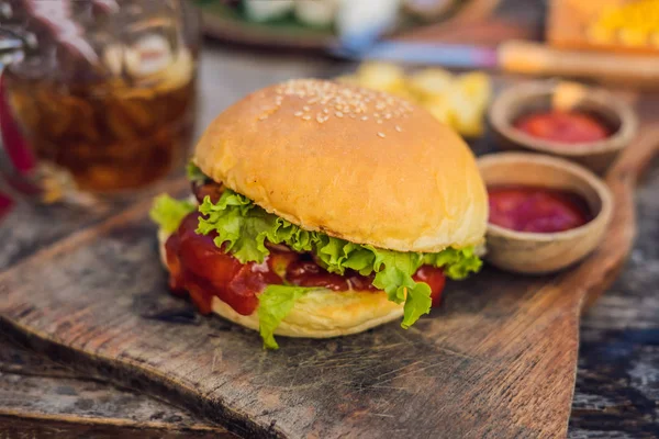 Closeup de hambúrguer fresco com batatas fritas em mesa de madeira com tigelas de molho de tomate. alimentos estilo de vida — Fotografia de Stock