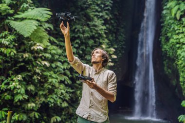 Adam orman ve şelale arka planı dron kontrol eder.