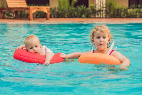 Irmão e irmã se divertindo na piscina em círculos infláveis — Fotografia de Stock