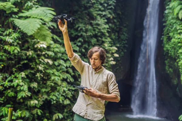 男は森と滝の背景にドローンを制御します。 — ストック写真