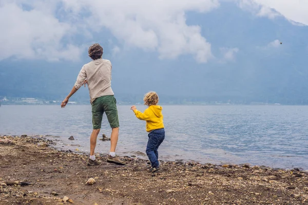 Vader en zoon op de lake Bratan en de bergen bedekt met wolken — Stockfoto