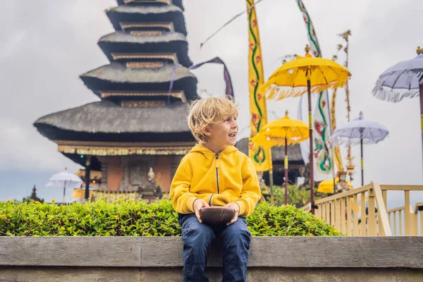 Boy traveler in the background of Pura Ulun Danu Bratan, Bali. Hindu temple surrounded by flowers on Bratan lake, Bali. Major Shivaite water temple in Bali, Indonesia. Hindu temple. Traveling with — Stock Photo, Image