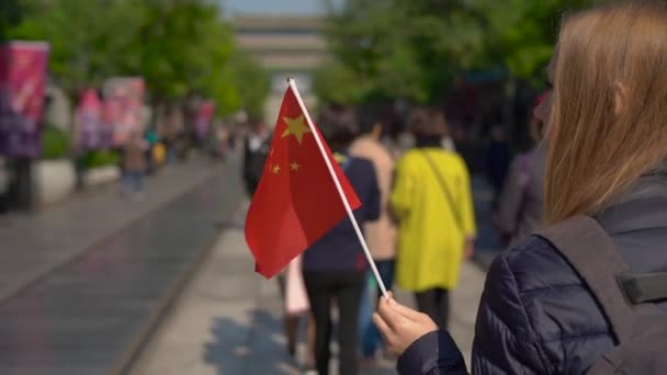 Lento movimiento de una joven bloguera sosteniendo una pequeña bandera china caminando por el centro comercial Quinmen Main Street. La Ciudad Prohibida en el centro de Beijing. la calle Caminante en el centro de la capital china — Vídeo de stock