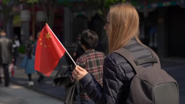 Lento movimiento de una joven bloguera sosteniendo una pequeña bandera china caminando por el centro comercial Quinmen Main Street. La Ciudad Prohibida en el centro de Beijing. la calle Caminante en el centro de la capital china — Vídeos de Stock